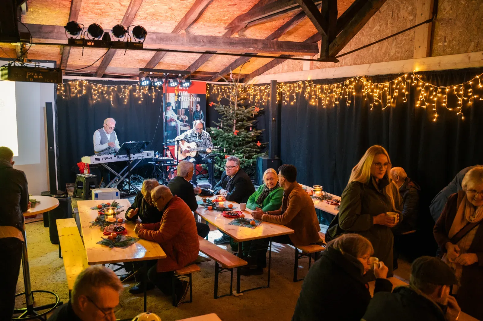Weihnachtsfeier im Kulturstellwerk Nordlippe mit Livemusik, Lichterketten und Gästen an festlichen Tischen
