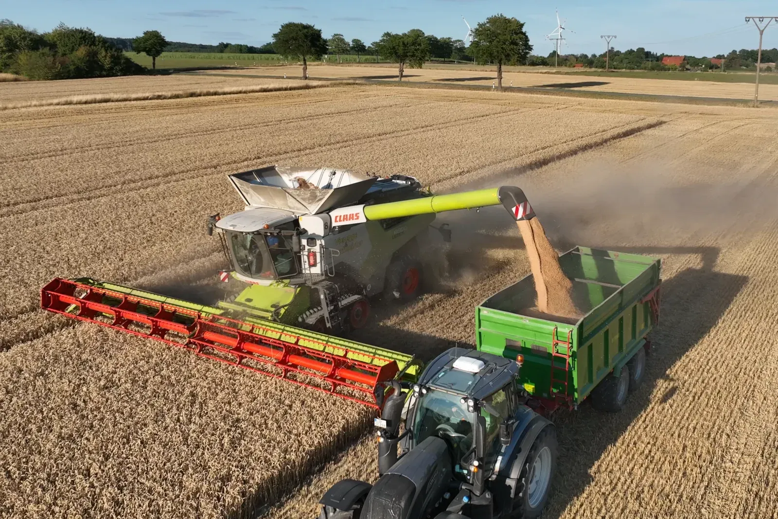Luftaufnahme: CLAAS LEXION 8800 überlädt im Abendlicht Korn auf einen Anhänger